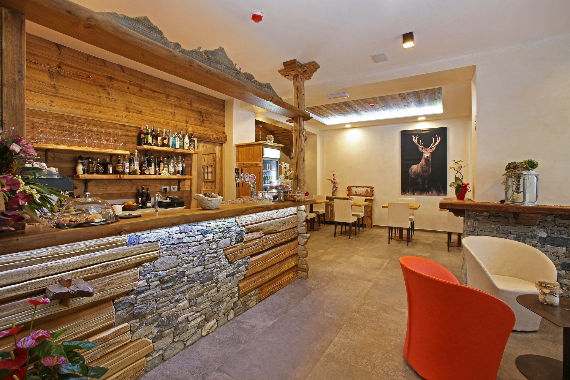 A rustic bar area with wooden shelves, stone accents, and a dining area with modern chairs and a table.