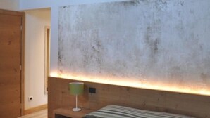 A bedroom with a wooden headboard, a bedside lamp, and a bed with striped bedding. - Casa Rosanna (Meolo)
