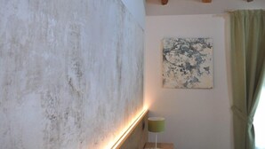 A room with a textured wall, a wooden ceiling, a green lamp, and a painting on the wall. - Casa Rosanna (Meolo)