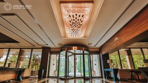A modern hotel lobby with a reflective floor, a central rotating door, and large windows offering a view of the outdoors. - Dreamland Oasis Resort & Spa (Kobuleti)