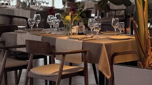 A dining table set for two with a view of the sea through large windows. - Dreamland Oasis Resort & Spa (Kobuleti)