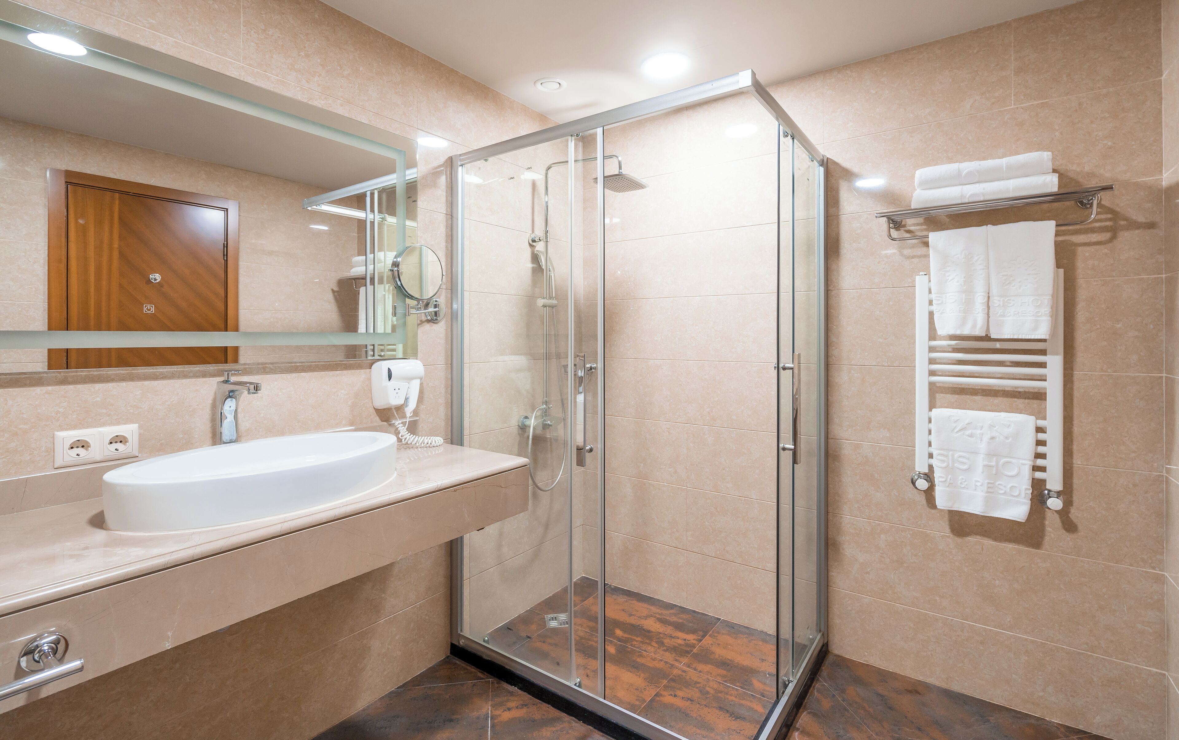 A modern bathroom with a glass-enclosed shower, a vanity with a sink, and a towel rack with multiple towels.