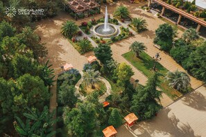 Vista aérea del patio del Hotel Dreamland Oasis, con una fuente central, rodeado de exuberante vegetación y áreas de estar al aire libre.