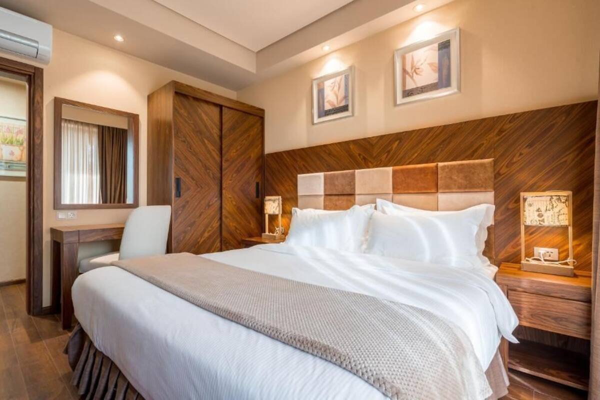 A hotel room with a large bed, a desk, and a wardrobe.