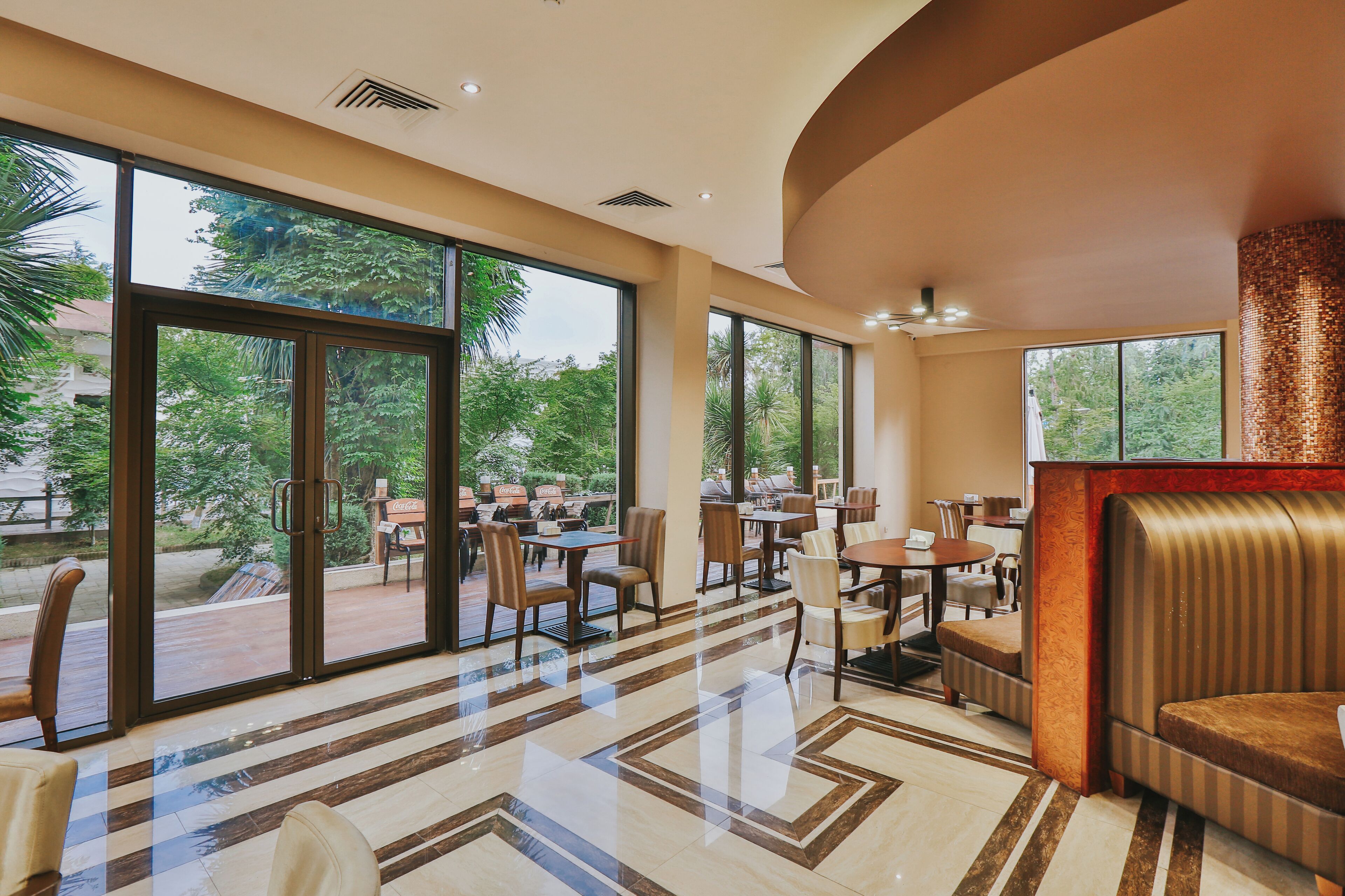 A spacious indoor area with large windows, a polished floor, and a seating area with tables and chairs.