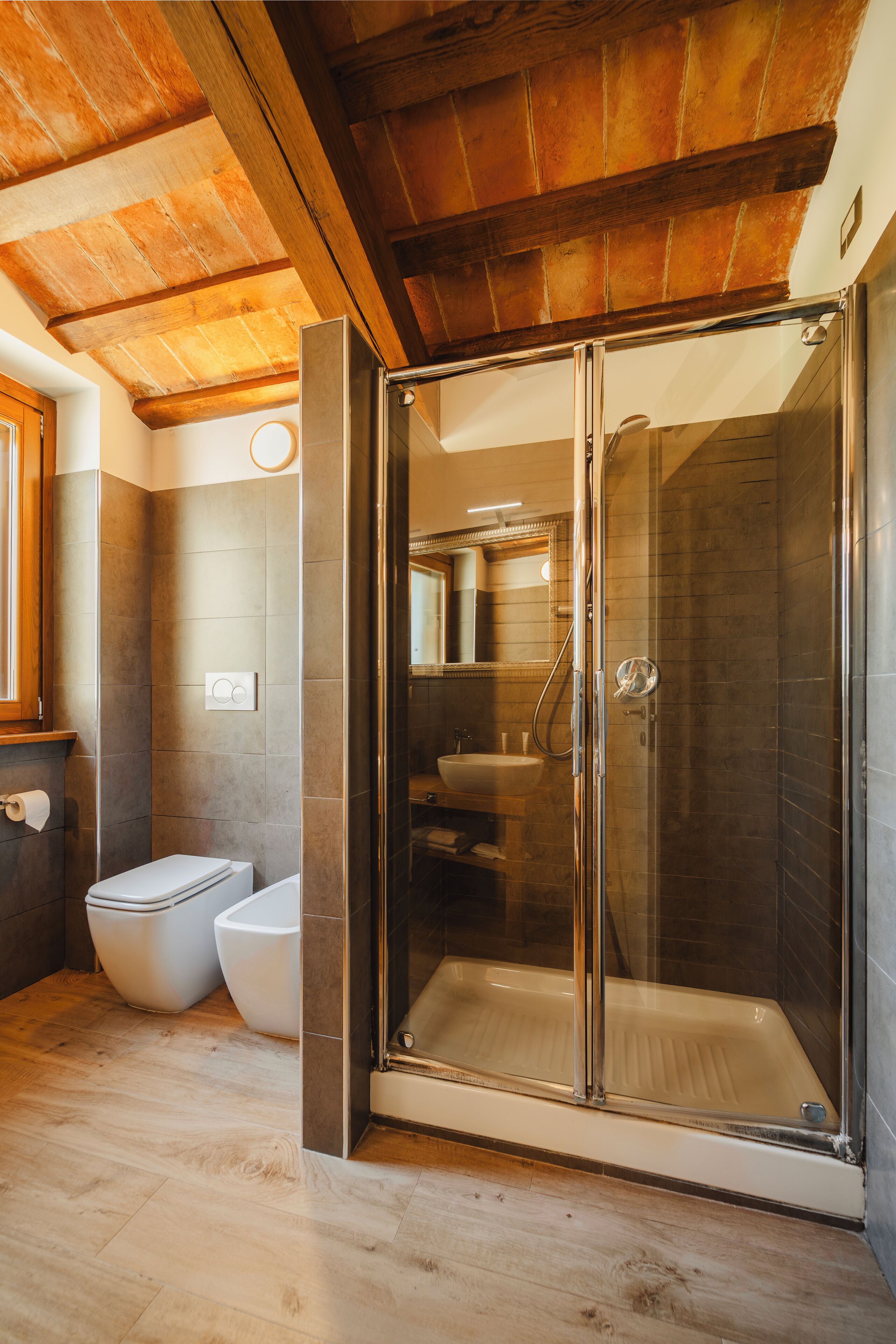 A modern bathroom with a glass-enclosed shower, a toilet, and a sink.