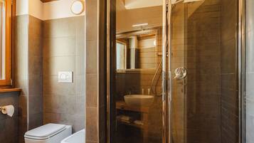 A modern bathroom with a glass-enclosed shower, a toilet, and a sink.