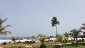 A beach with thatched umbrellas, wooden lounge chairs, and palm trees. - Rlj Kendeja Resort and Villas (Monrovia)