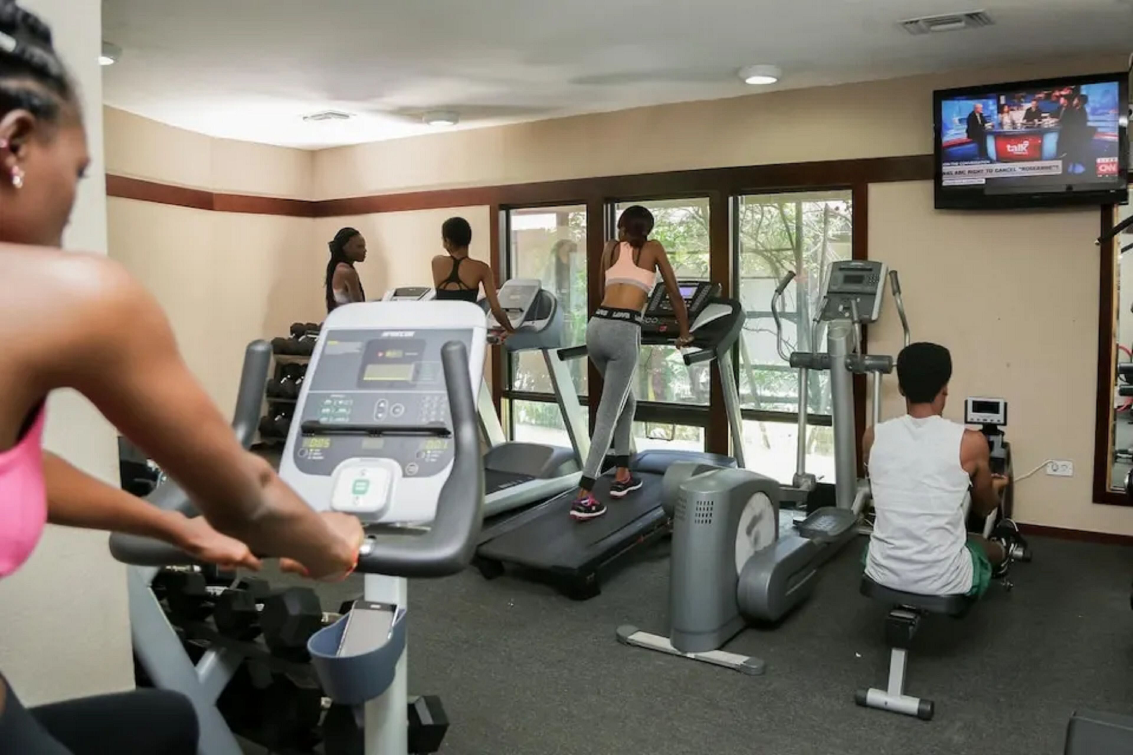 Une salle de sport équipée de tapis de course, de vélos d’appartement et d’un écran de télévision.