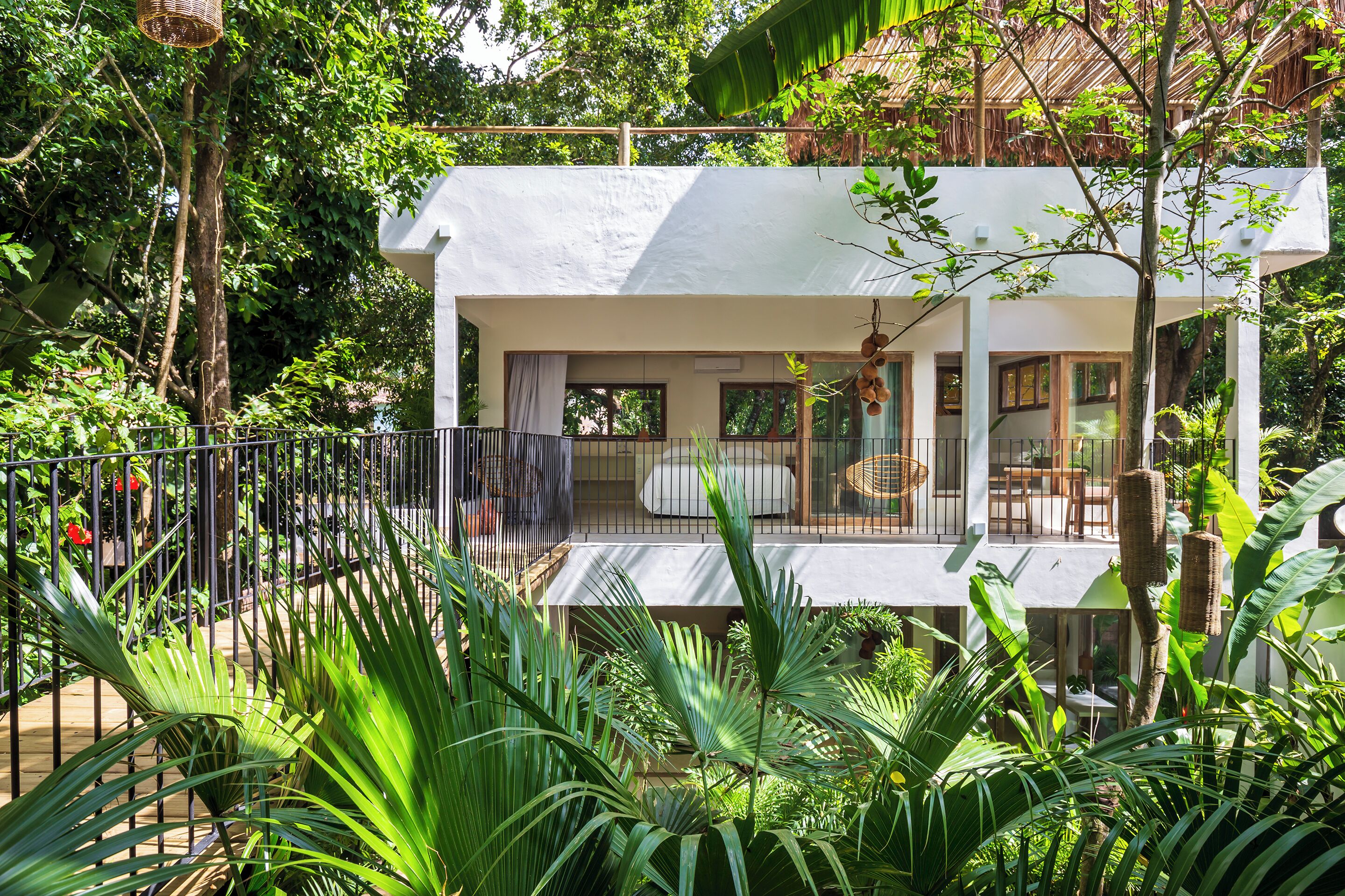 A modern house with a balcony, surrounded by lush greenery.