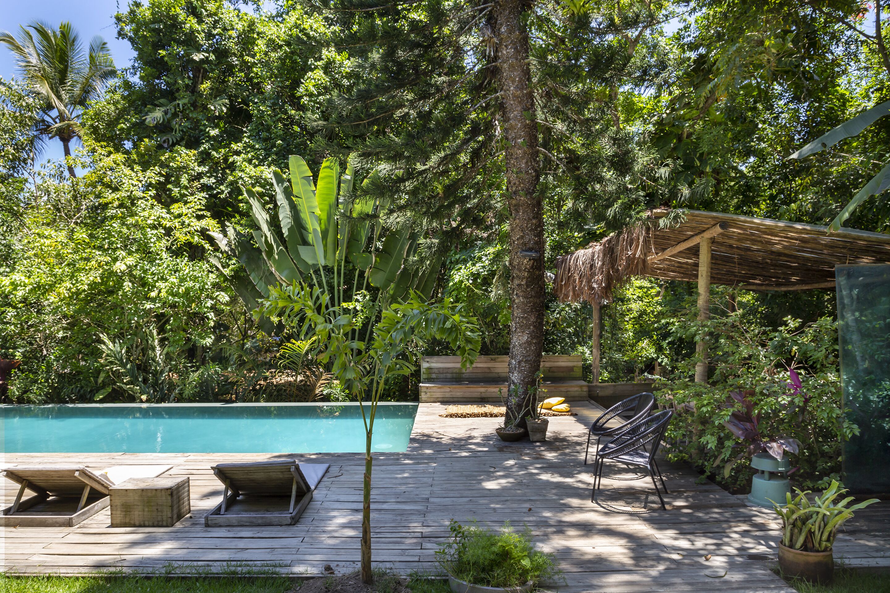 Une terrasse en bois avec une piscine, des chaises longues et une pergola.