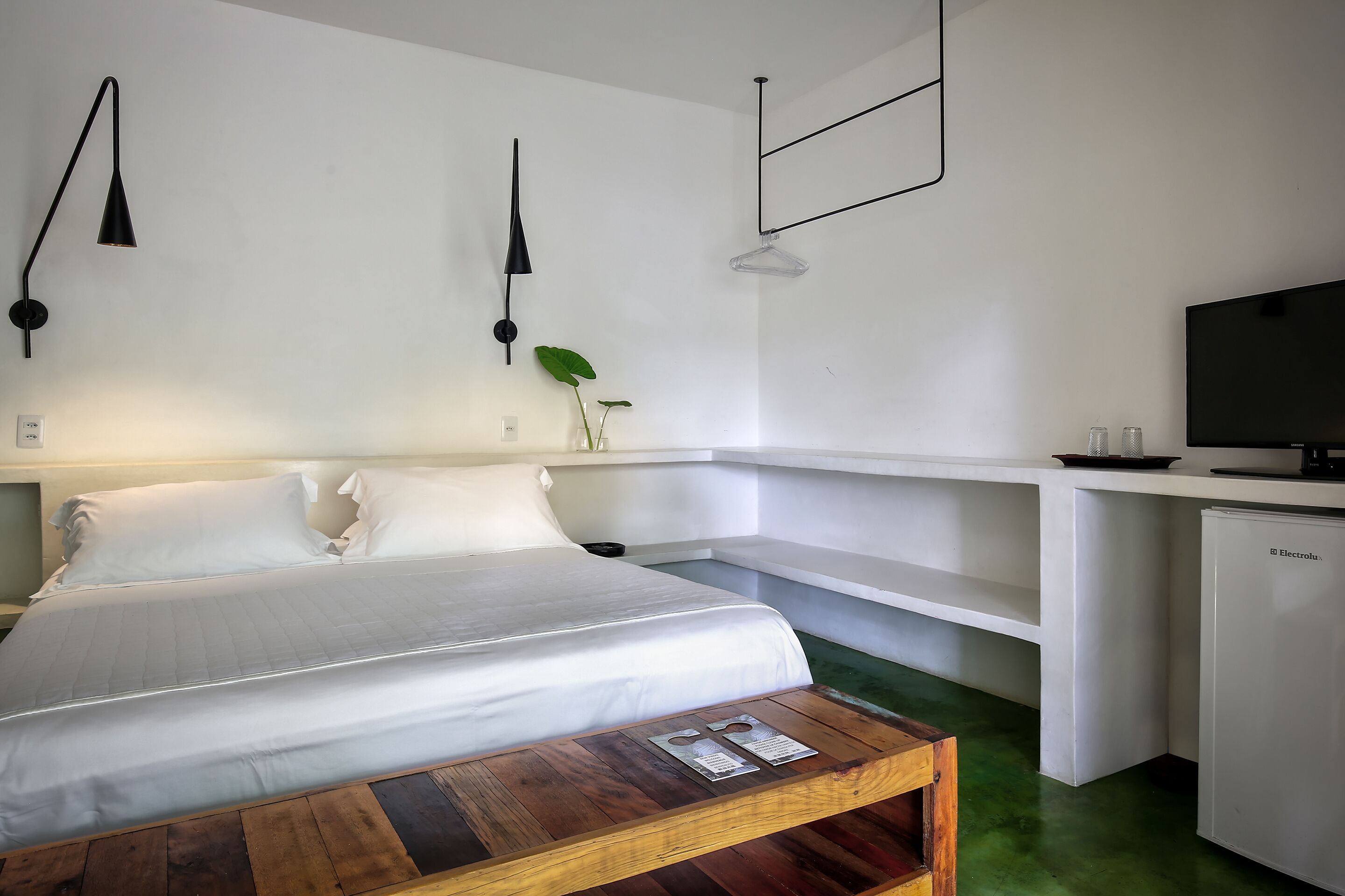 A modern hotel room with a bed, bedside table, desk, and a television.