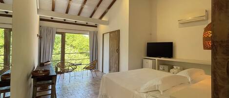 A bedroom with a large bed, a TV, and a balcony with chairs and a table.