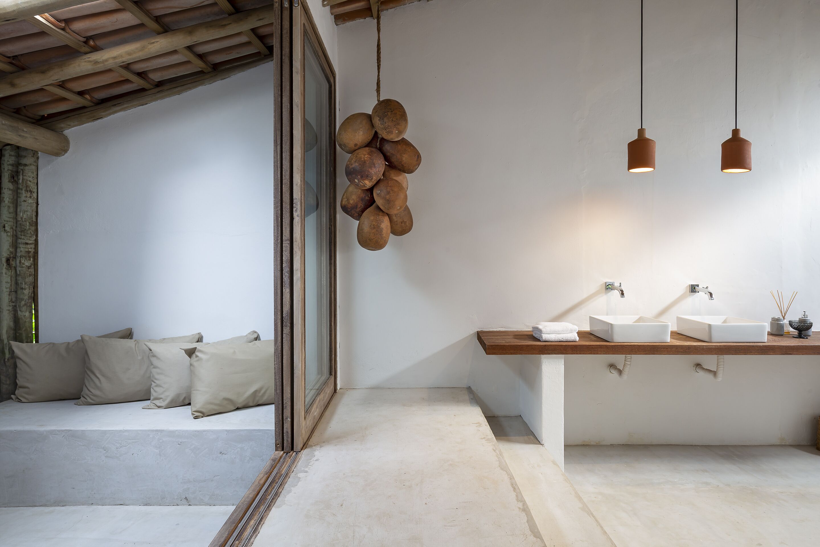 A modern bathroom with a wooden vanity, two white sinks, and a hanging light fixture.