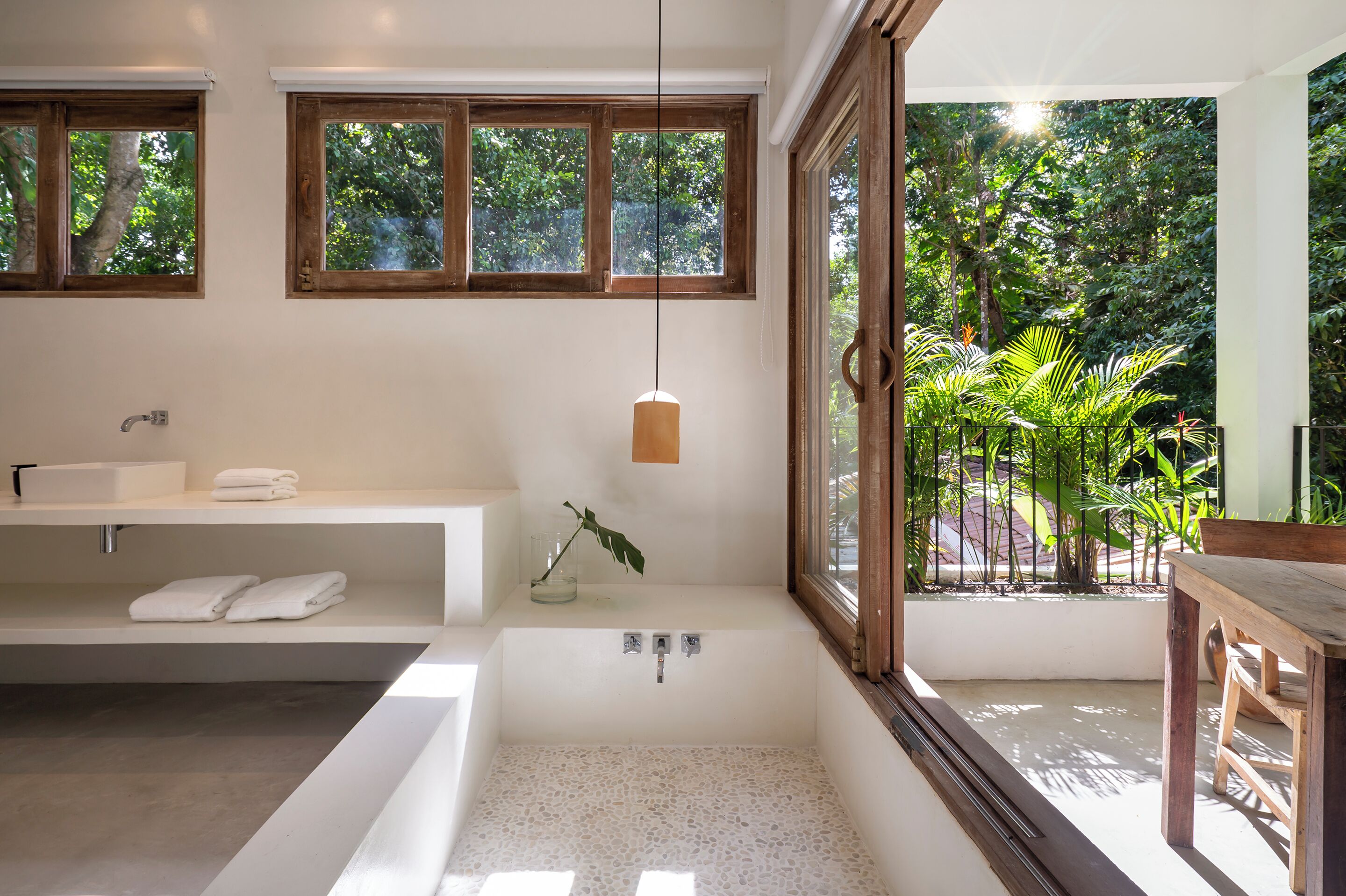 Une salle de bain moderne avec une baignoire, un meuble-lavabo et une grande fenêtre.