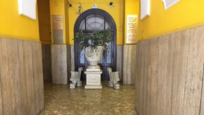 Un couloir doté d’un sol carrelé, d’un grand bac à plantes et de panneaux indiquant les noms des hôtels et les numéros des étages.