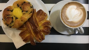 Une assiette de pâtisseries et une tasse de café sur une table à rayures.