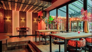 Eine moderne Bar mit Holztischen und -hocker, einem großen Fenster mit Aussicht und Zierpflanzen.