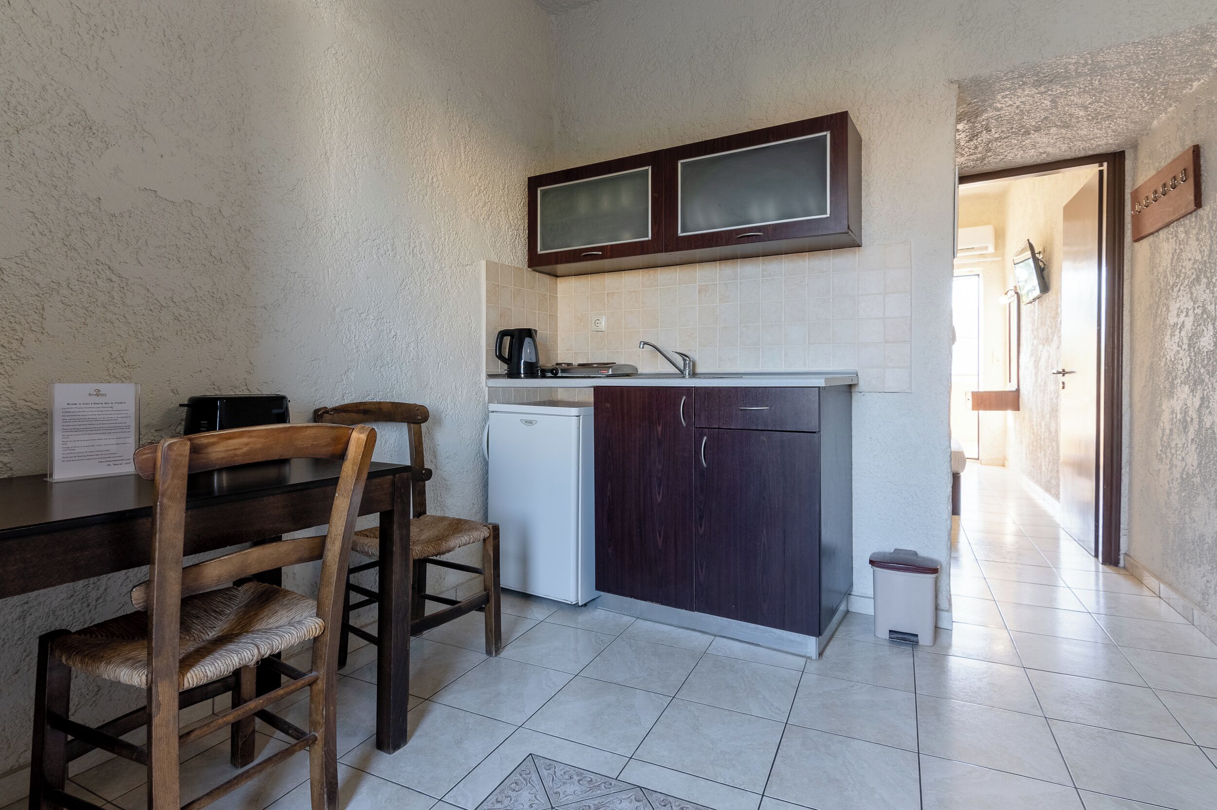Una cocina compacta con una mesa y sillas, un refrigerador pequeño y un lavamanos.