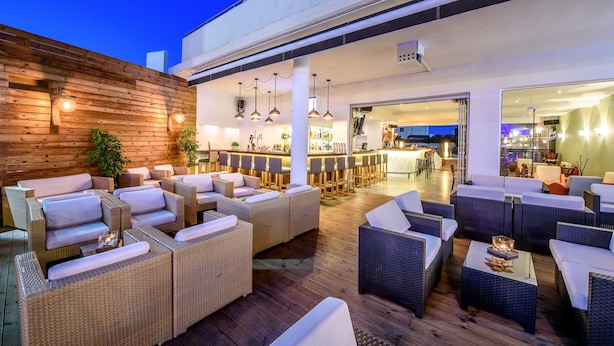 Een terras met rieten meubilair en een bar op de achtergrond.