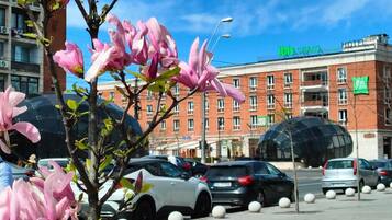 A parking lot with cars and a building with a green sign that reads 'ibis styles.'