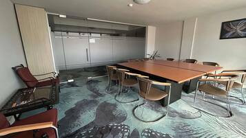 A conference room with a long table, chairs, a red chair, a glass table, and a patterned carpet.
