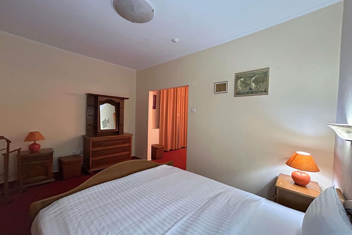 Ein Hotelzimmer mit Bett, Schminktisch, Spiegel, Lampe und einem fenster mit Vorhängen.