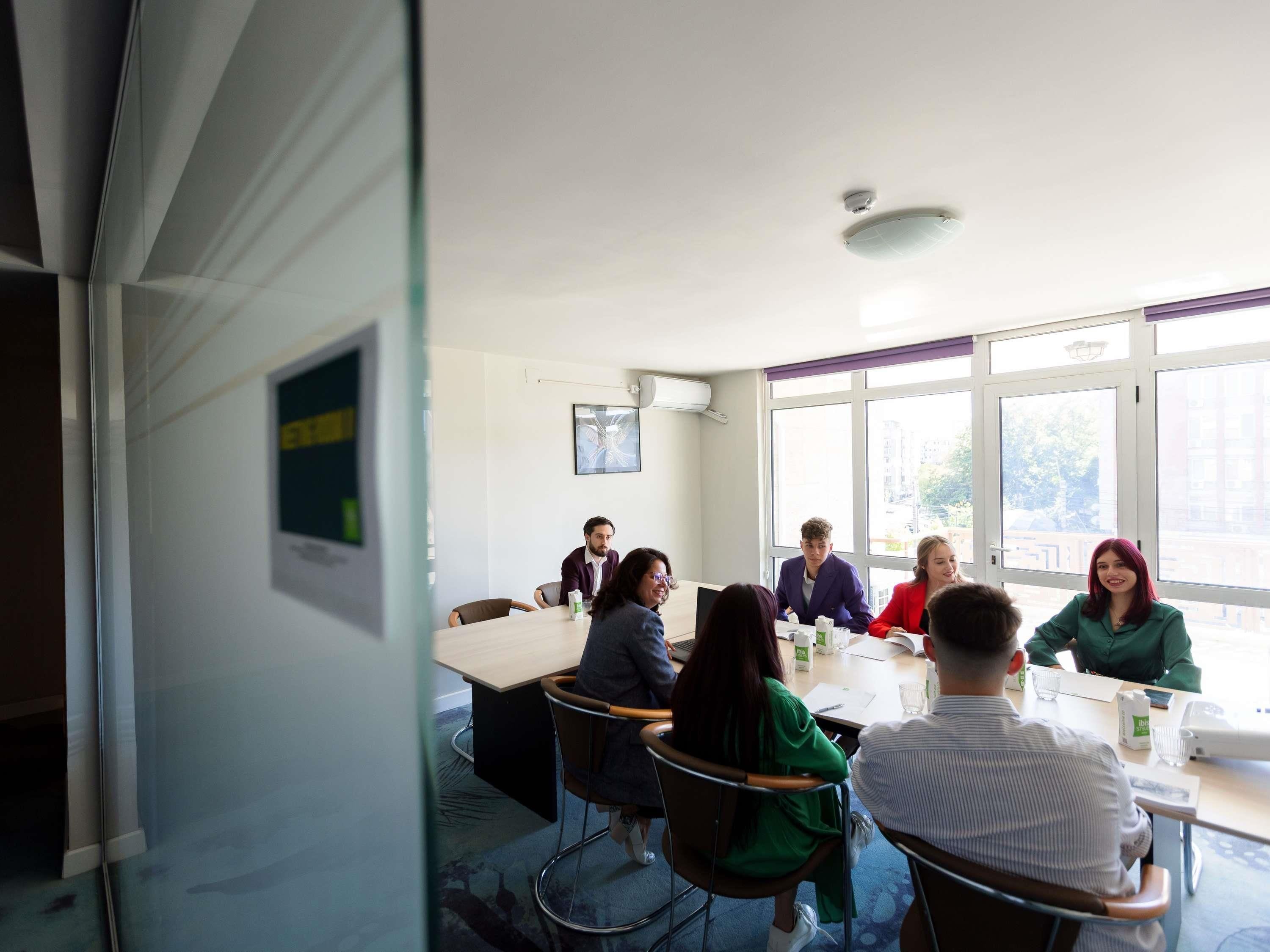 A conference room with a long table, chairs, and a large window.