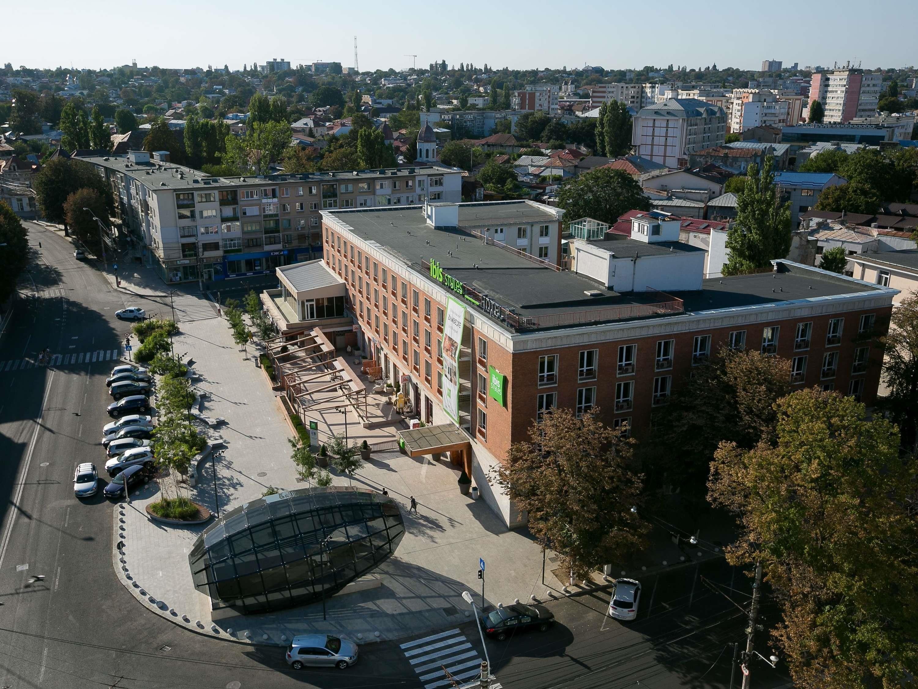 Ein mehrgeschossiges Gebäude mit flachem Dach, einem Parkplatz und einem Fußweg.