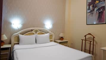 Een hotelkamer met een bed, nachtlampjes, een nachtkastje en een aan de muur hangend schilderij.