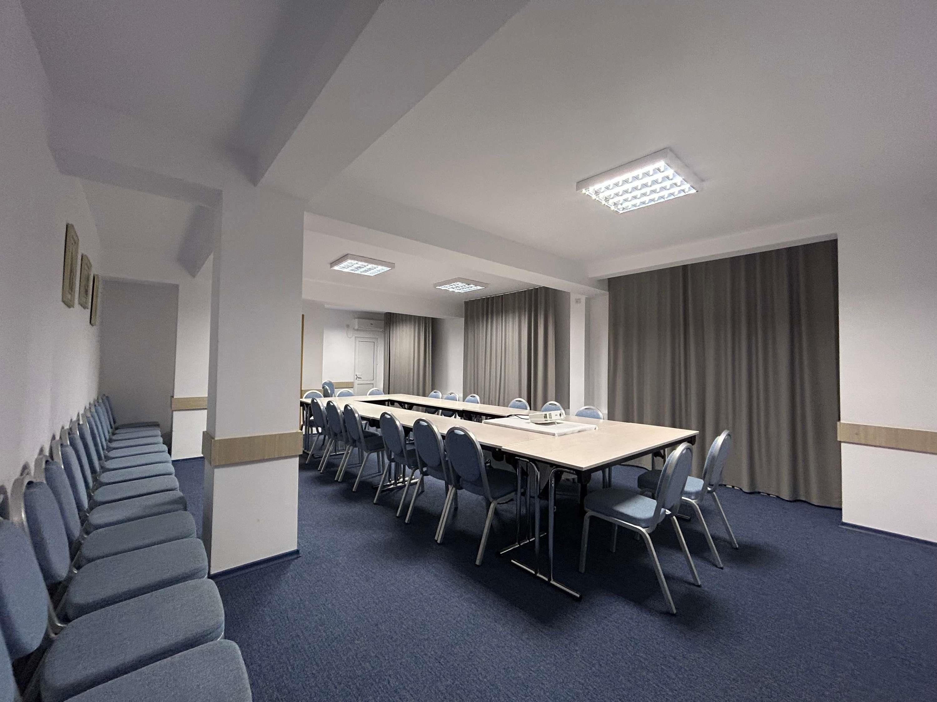 A conference room with a long table, chairs, and a carpeted floor.