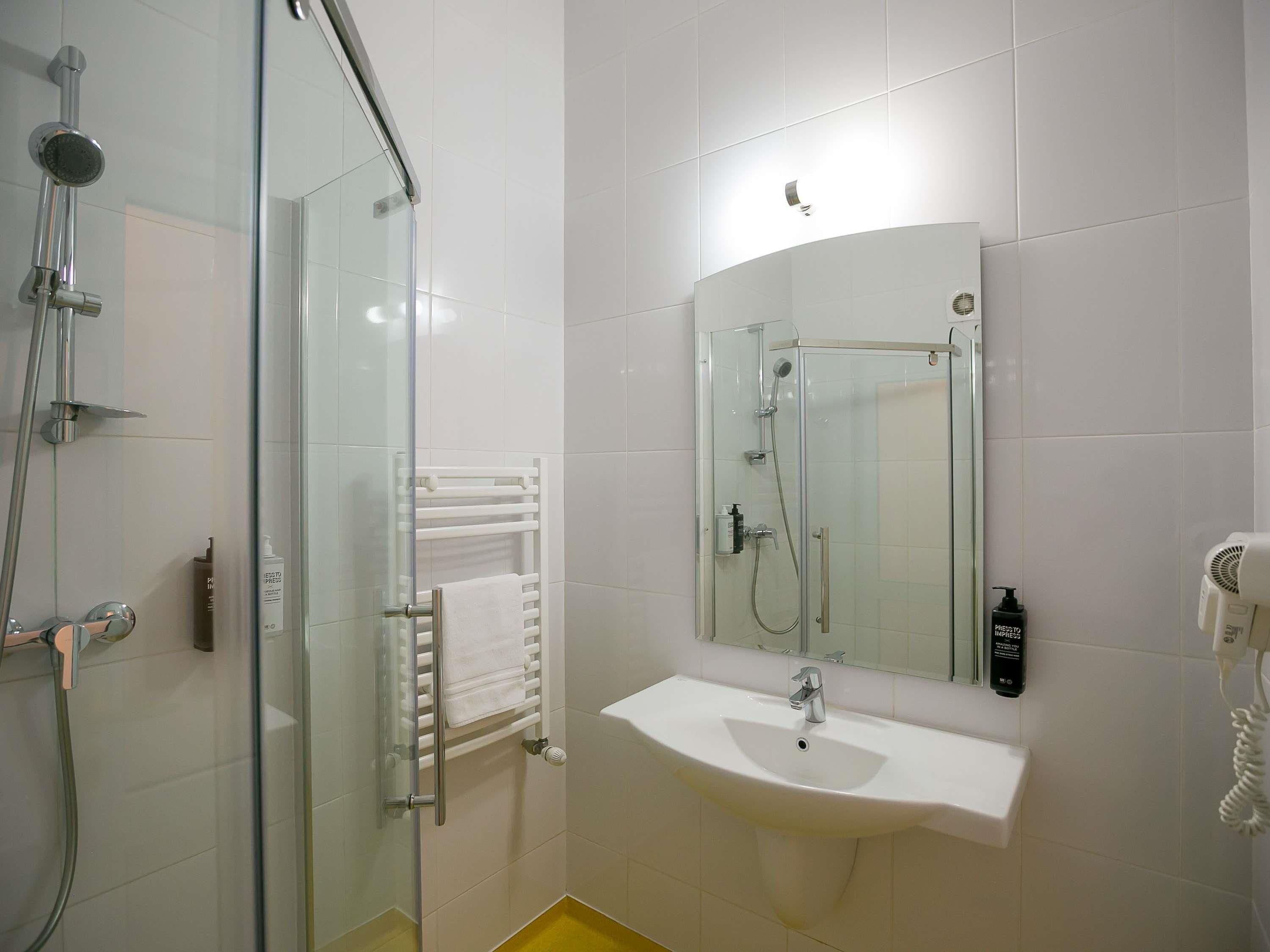 A modern bathroom with a glass-enclosed shower, a white sink, and a mirror above it.