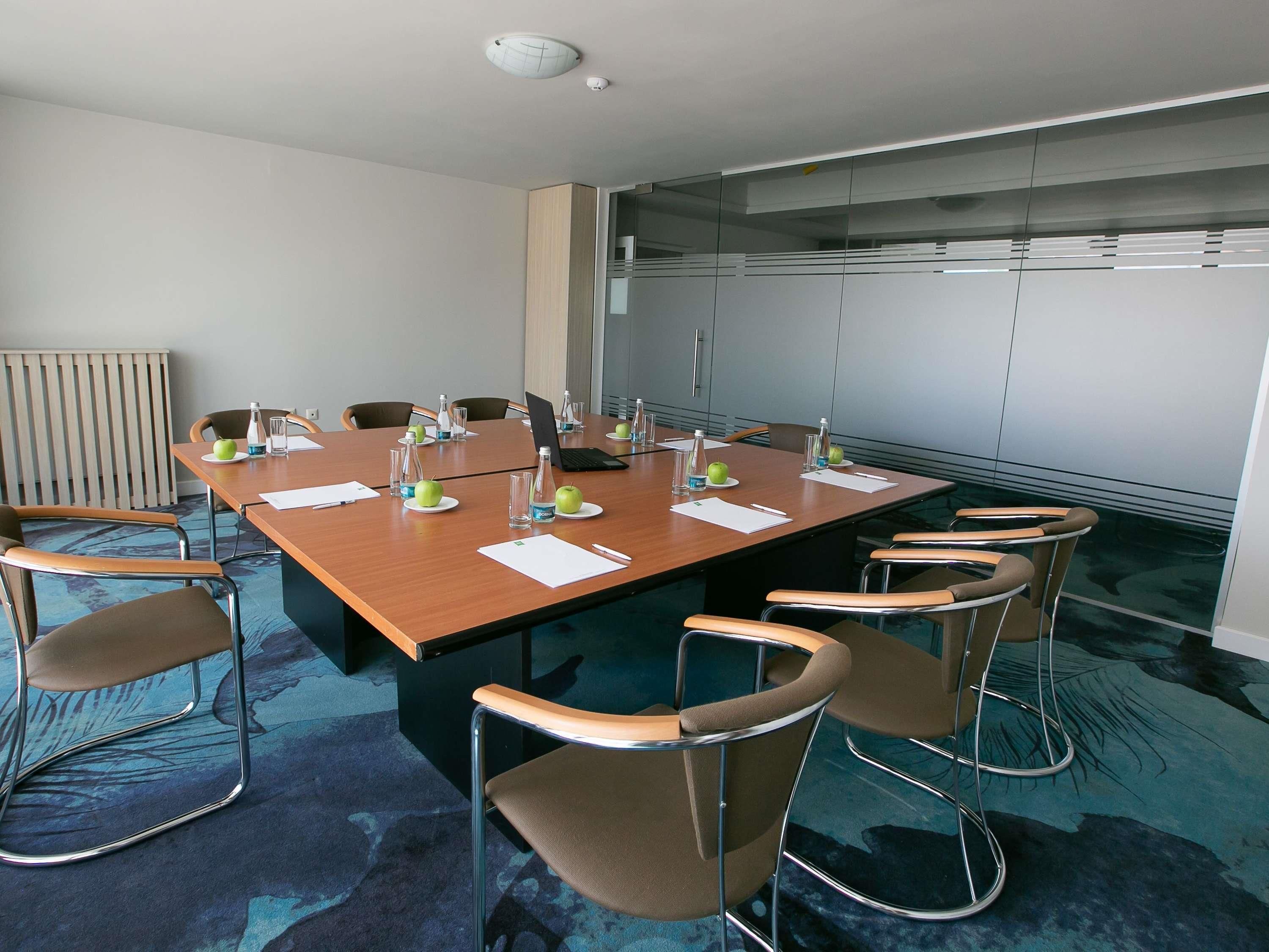 A conference room with a long table, chairs, and a laptop.