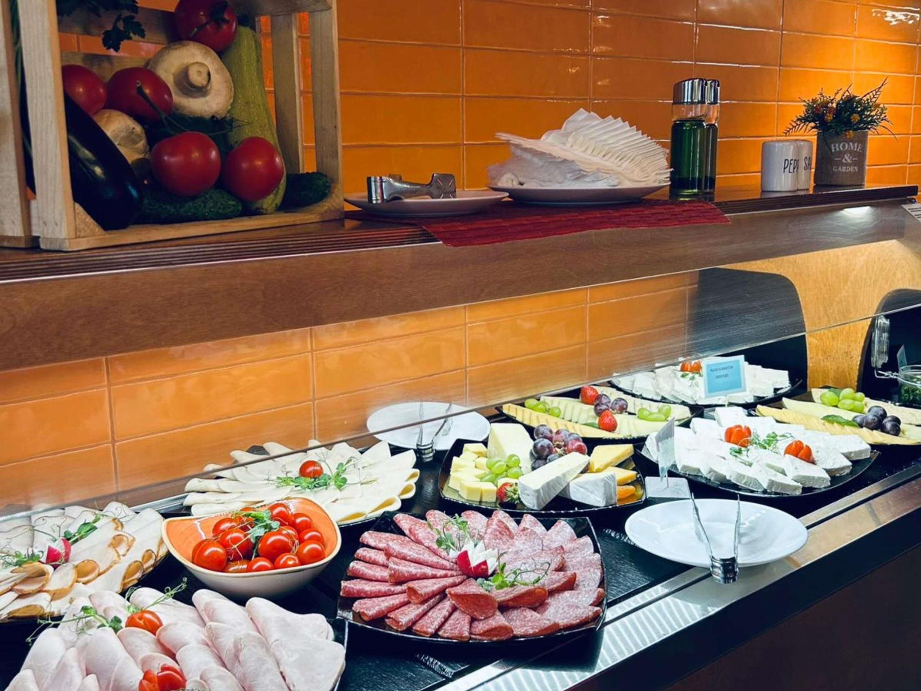 A buffet with various food items including cheeses, meats, and vegetables.