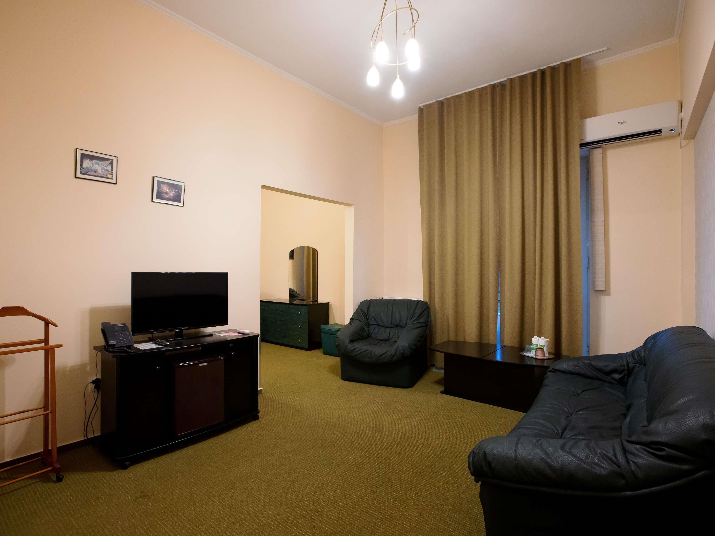 A living room with a flat-screen TV, a sofa, a chair, a small table, and a cabinet.