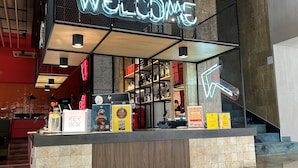 A reception area with a neon 'WELCOME' sign, a KEYSER BOX display, and a variety of products on shelves. - ibis Styles Dunarea Galati (Galati)