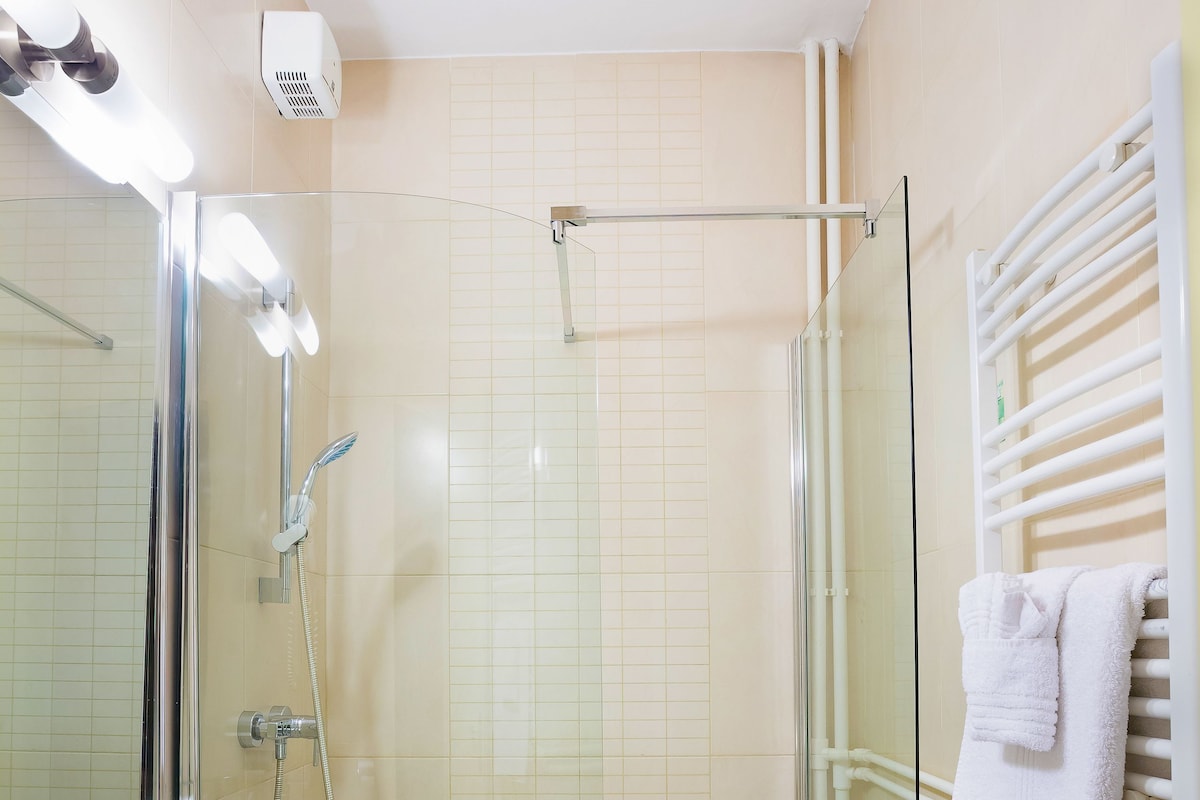 Een moderne badkamer met een douchecabine van glas, een wit wastafelmeubel en een glazen bad.