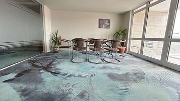 Un salón de conferencias con separador de vidrio, alfombra estampada y vistas amplias a través de grandes ventanales.