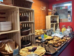Un buffet de petit-déjeuner comprenant du pain, des viennoiseries et des fruits.