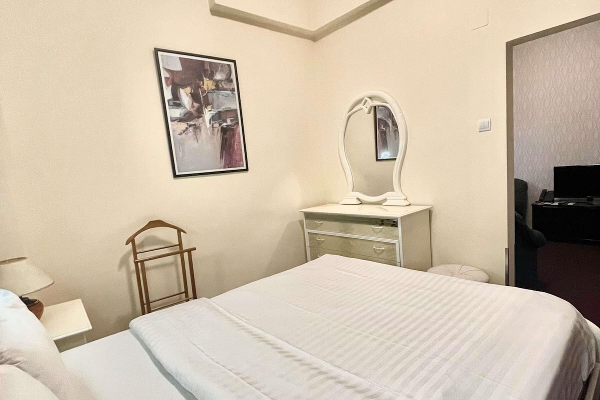 Ein Hotelzimmer mit Bett, Schminktisch, Spiegel, kleinem Tisch und Fernseher.