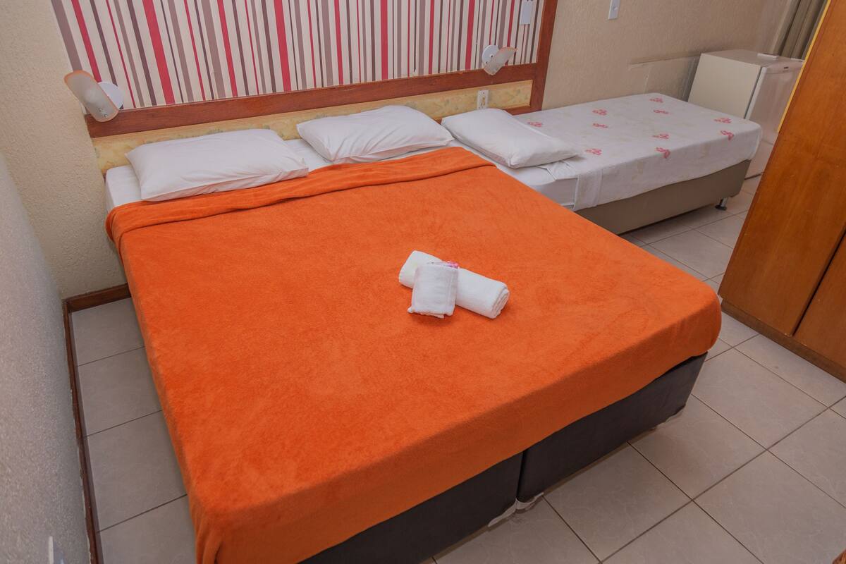 A hotel room with a bed, a small table, and a chair.