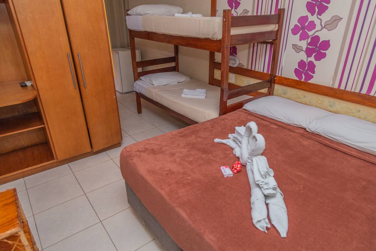 A bunk bed room with a red mattress, wooden wardrobe, and a floral wall decoration.