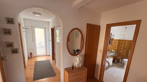 A hallway leading to a bathroom with a wooden dresser, a mirror, and a small statue. - Apartment Hope Inn (Gross-Zimmern)