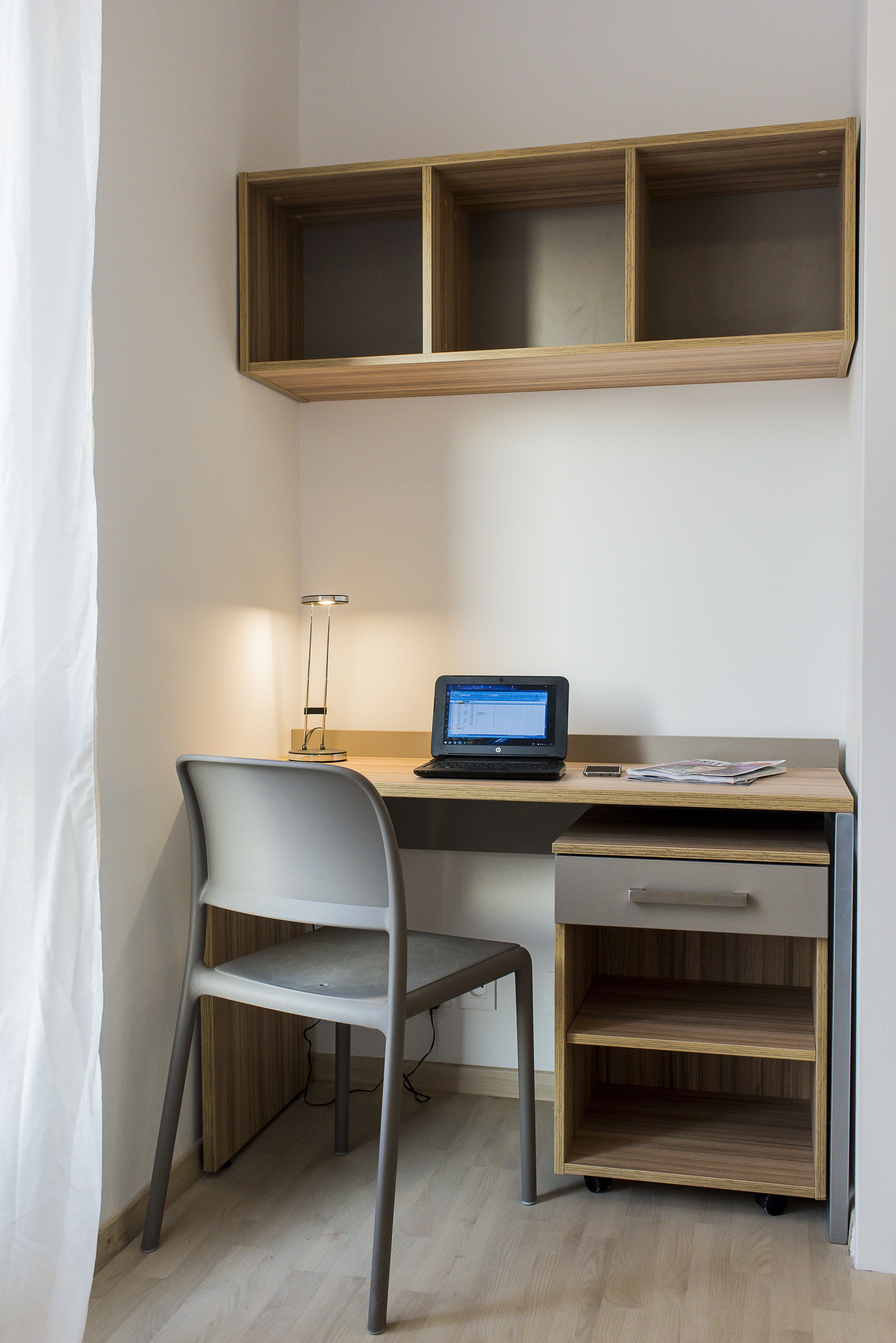 Een modern bureau met een laptop, een stoel en een bureaulamp.