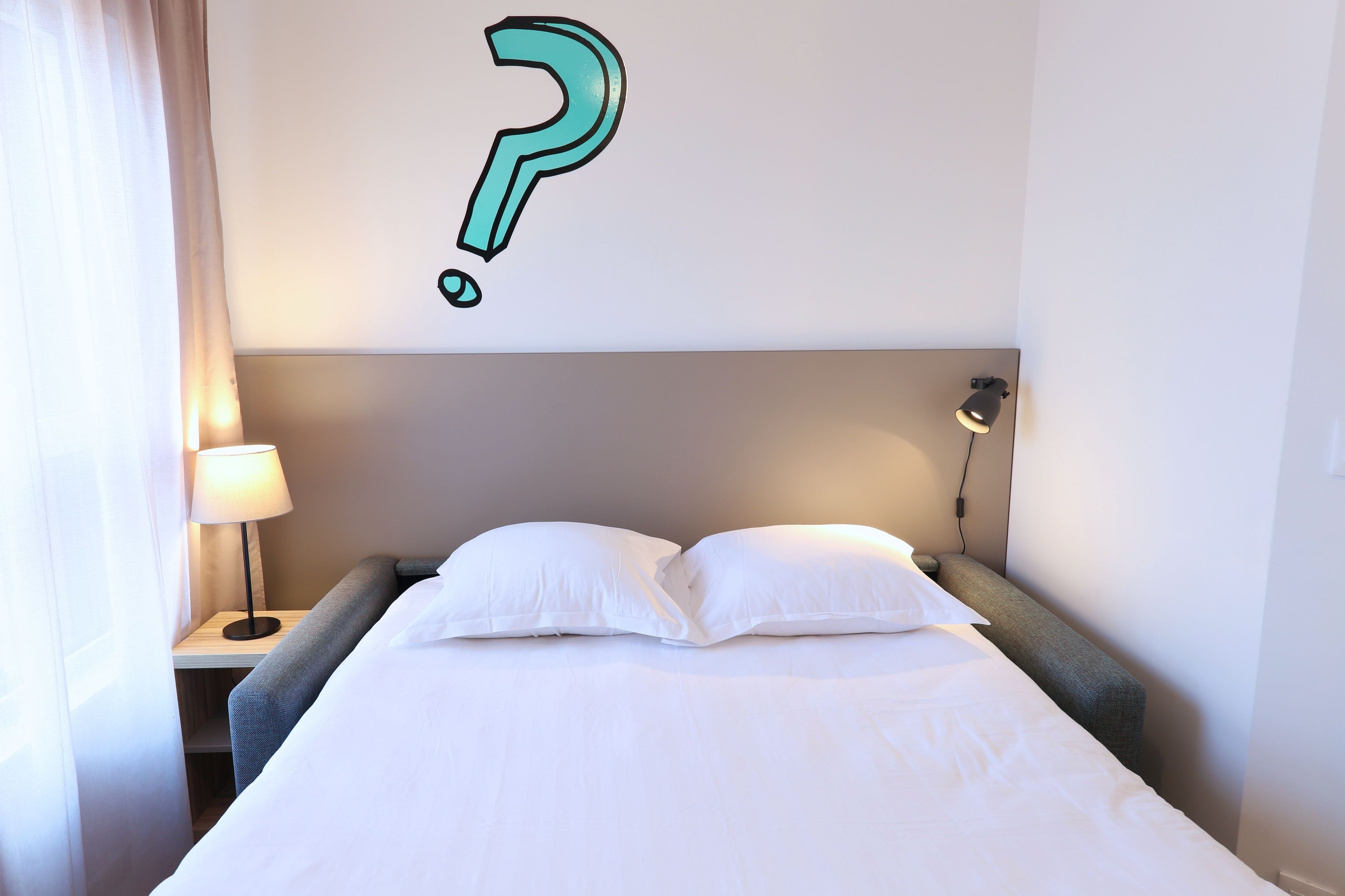 Ein Hotelzimmer mit Bett, Nachttisch mit Lampe und Wandleuchte.