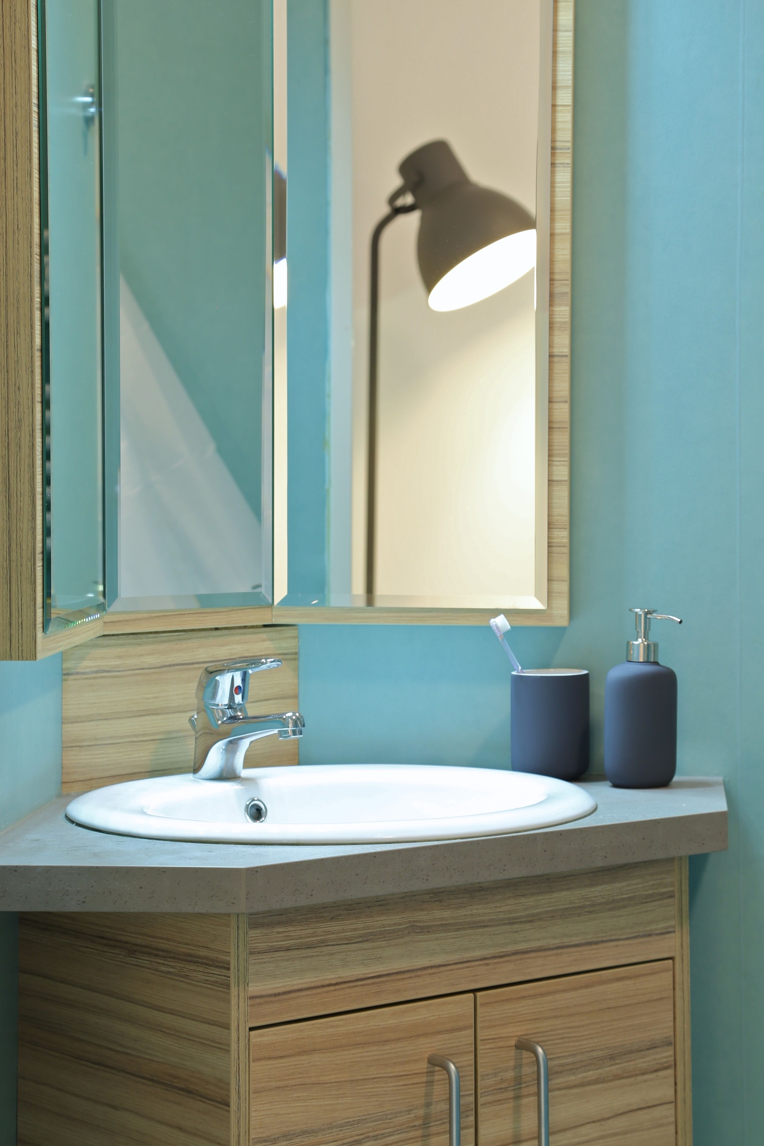 A bathroom with a sink, mirror, and a lamp.