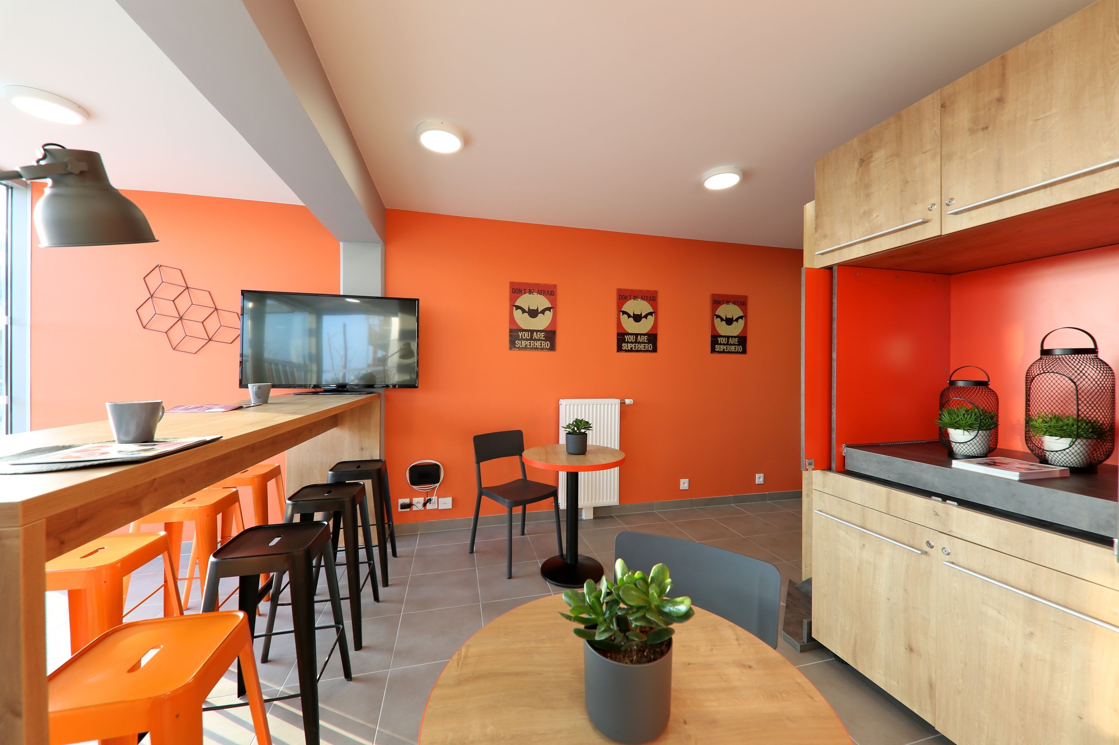 A modern kitchen with orange walls, wooden cabinets, and a central island with seating.