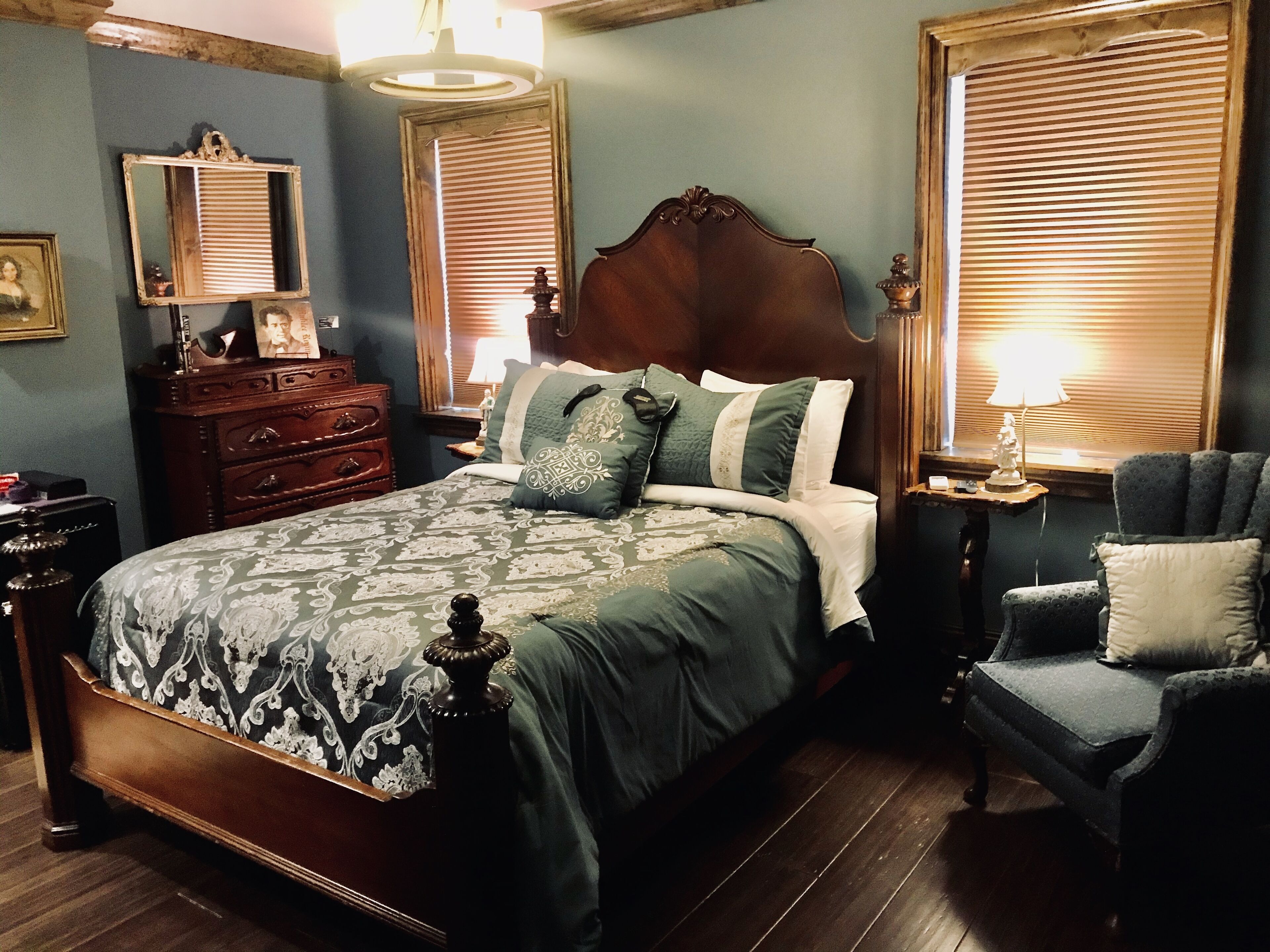 Une chambre à coucher avec un grand lit, une commode, une chaise et une table de chevet avec une lampe.