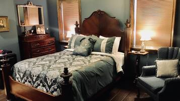 Une chambre à coucher avec un grand lit, une commode, une chaise et une table de chevet avec une lampe.