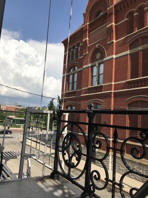 A red brick building with arched windows and a balcony railing.